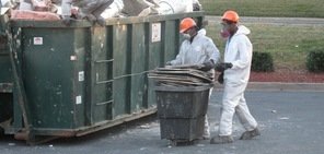 Water Damage Restoration Technicians Removing Debris To Street Dumpster
